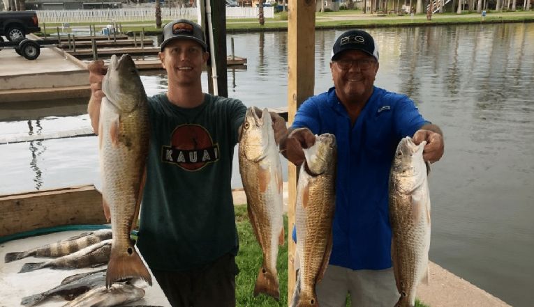 Two men holding two fish caught.