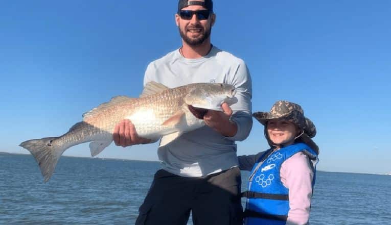 A man holding a white big fish with a child.